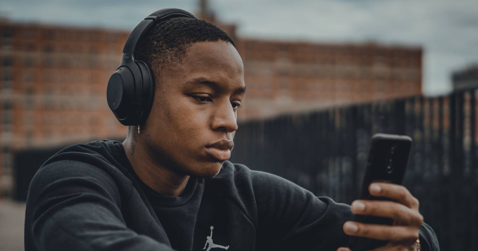 Молодой человек слушает музыку в наушниках на смартфоне
