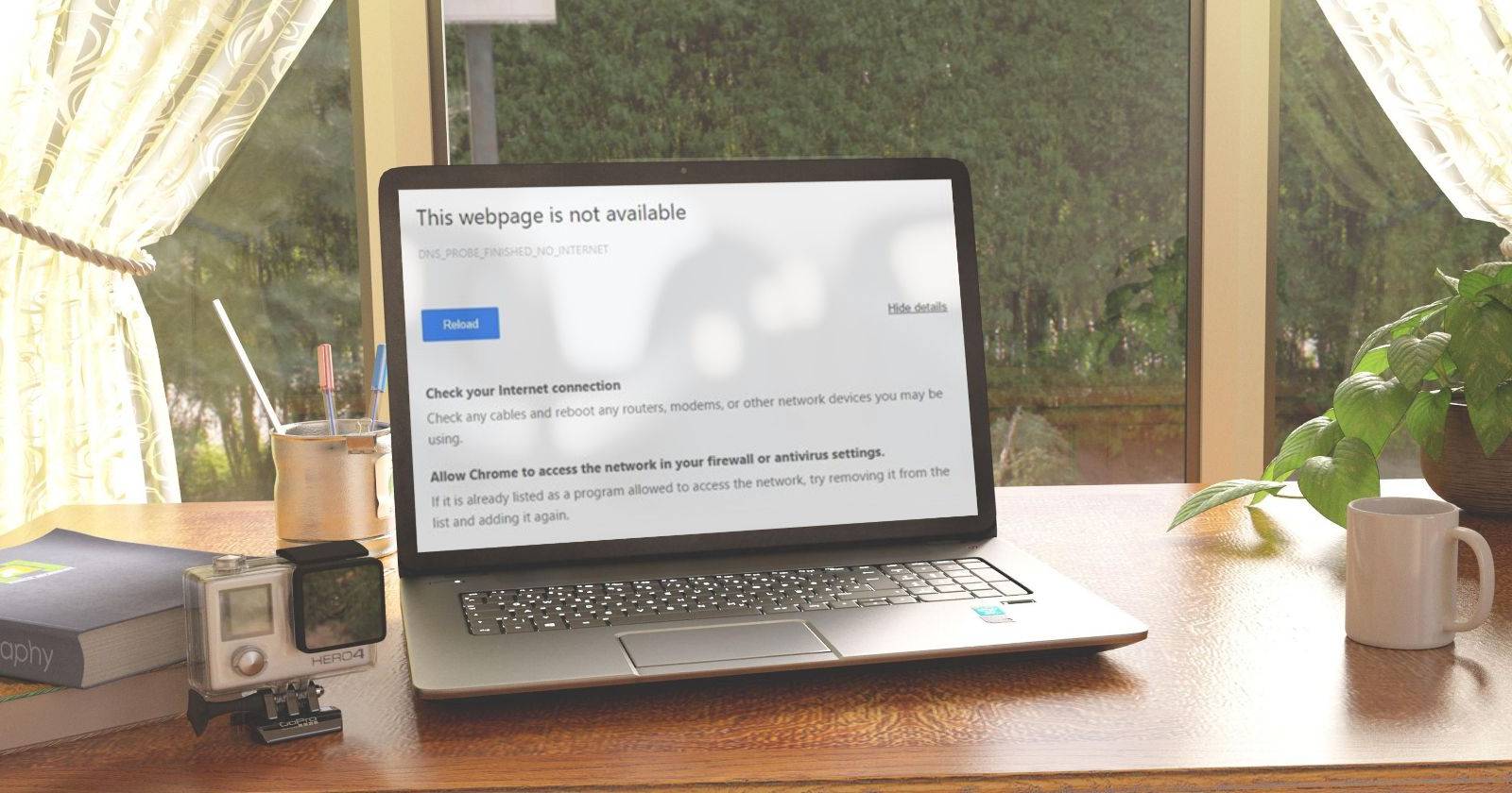Ноутбук на столе у окна с открытым Chrome, показывающим сообщение о необходимости разрешить Chrome доступ через брандмауэр