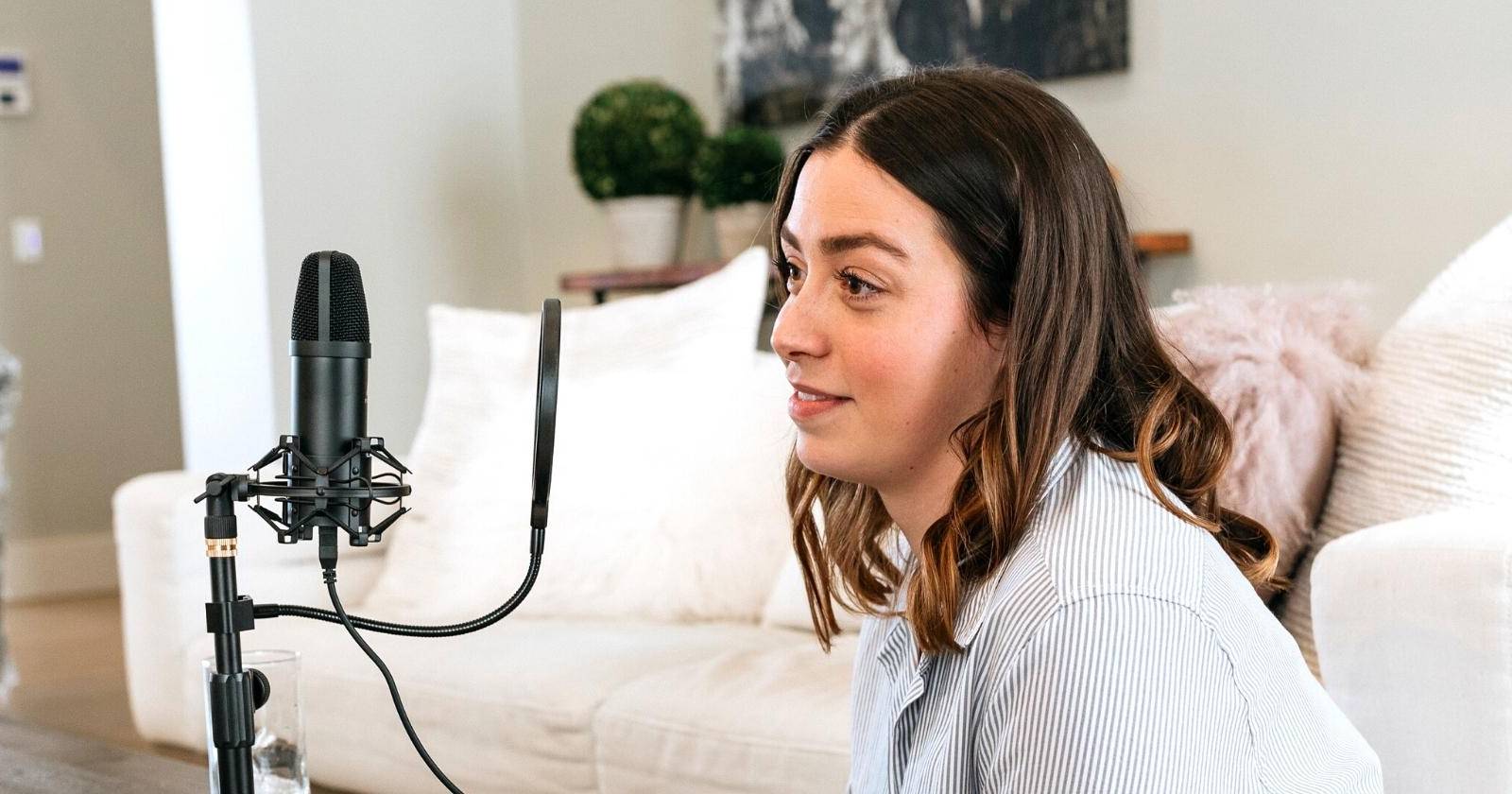 Женщина-подкастер смотрит на микрофон