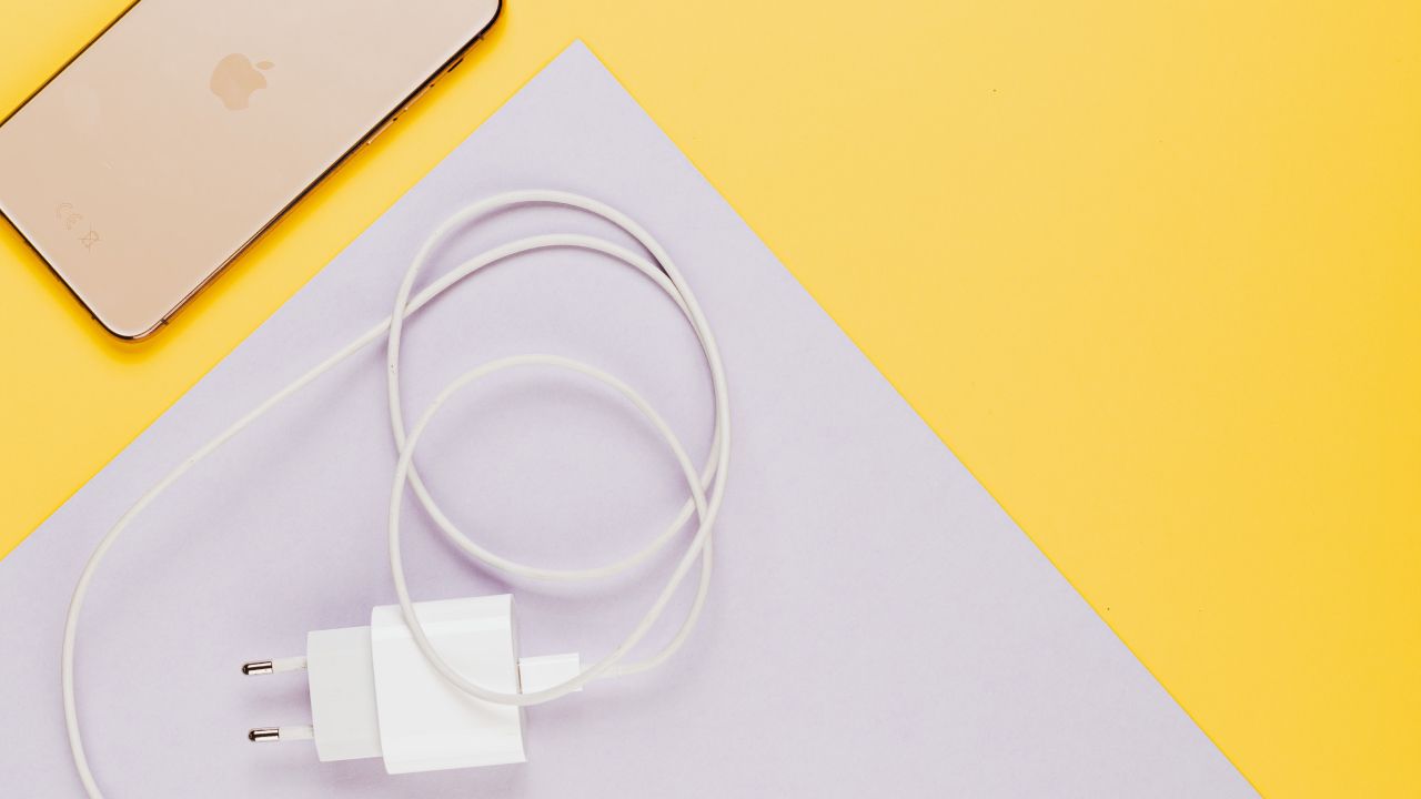 Зарядное устройство рядом с iPhone на жёлтом фоне