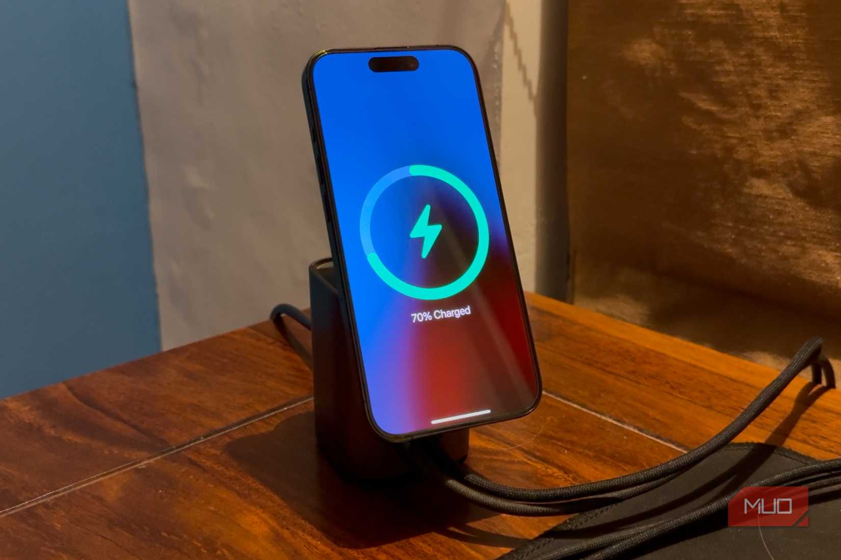 iPhone, установленный на беспроводное зарядное MagSafe на столе