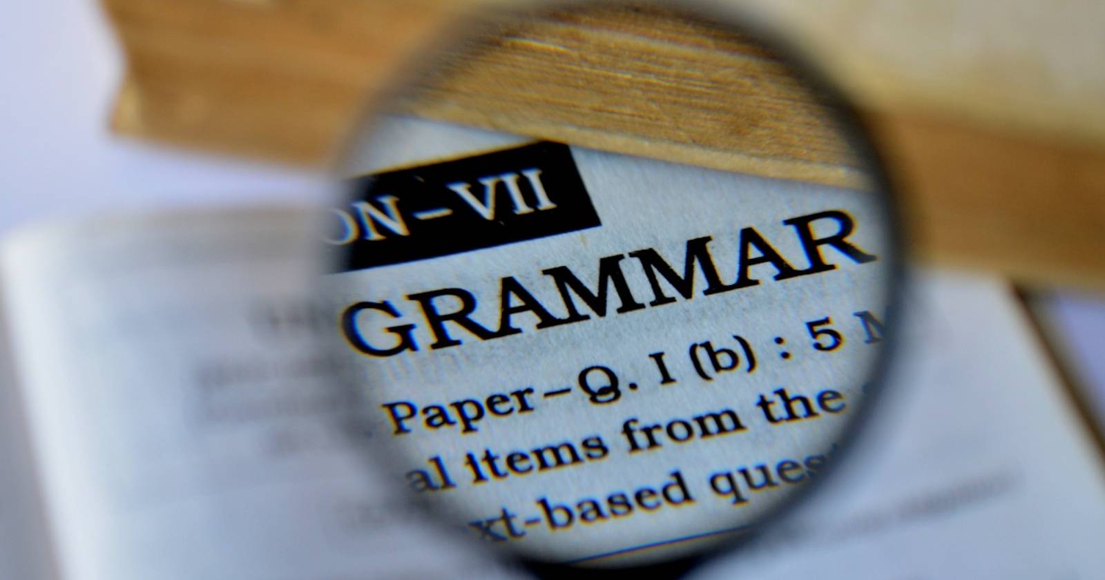 лупа, показывающая слово «grammar» на бумаге
