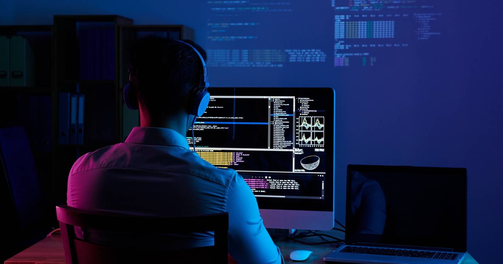 Разработчик за компьютером работает с кодом и интерфейсами