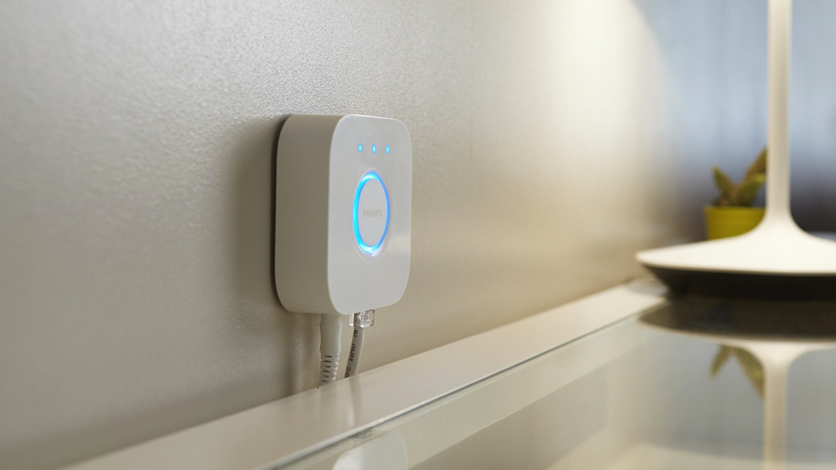 Мост Philips Hue, установленный на стене.
