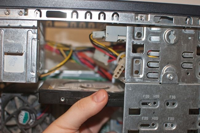 Mano sosteniendo disco duro por los lados evitando tocar el circuito
