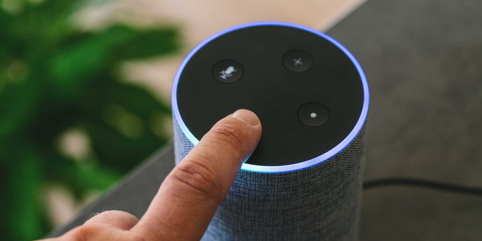 Умная колонка Amazon Echo с пальцем пользователя, нажимающим кнопку