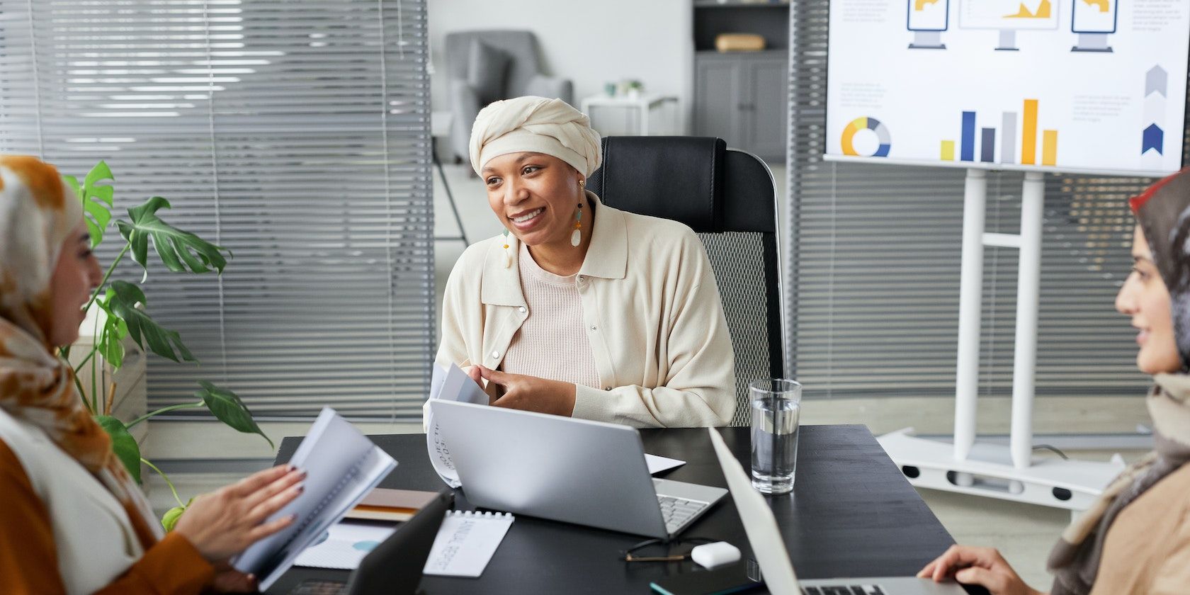 Три женщины сидят за столом с ноутбуками