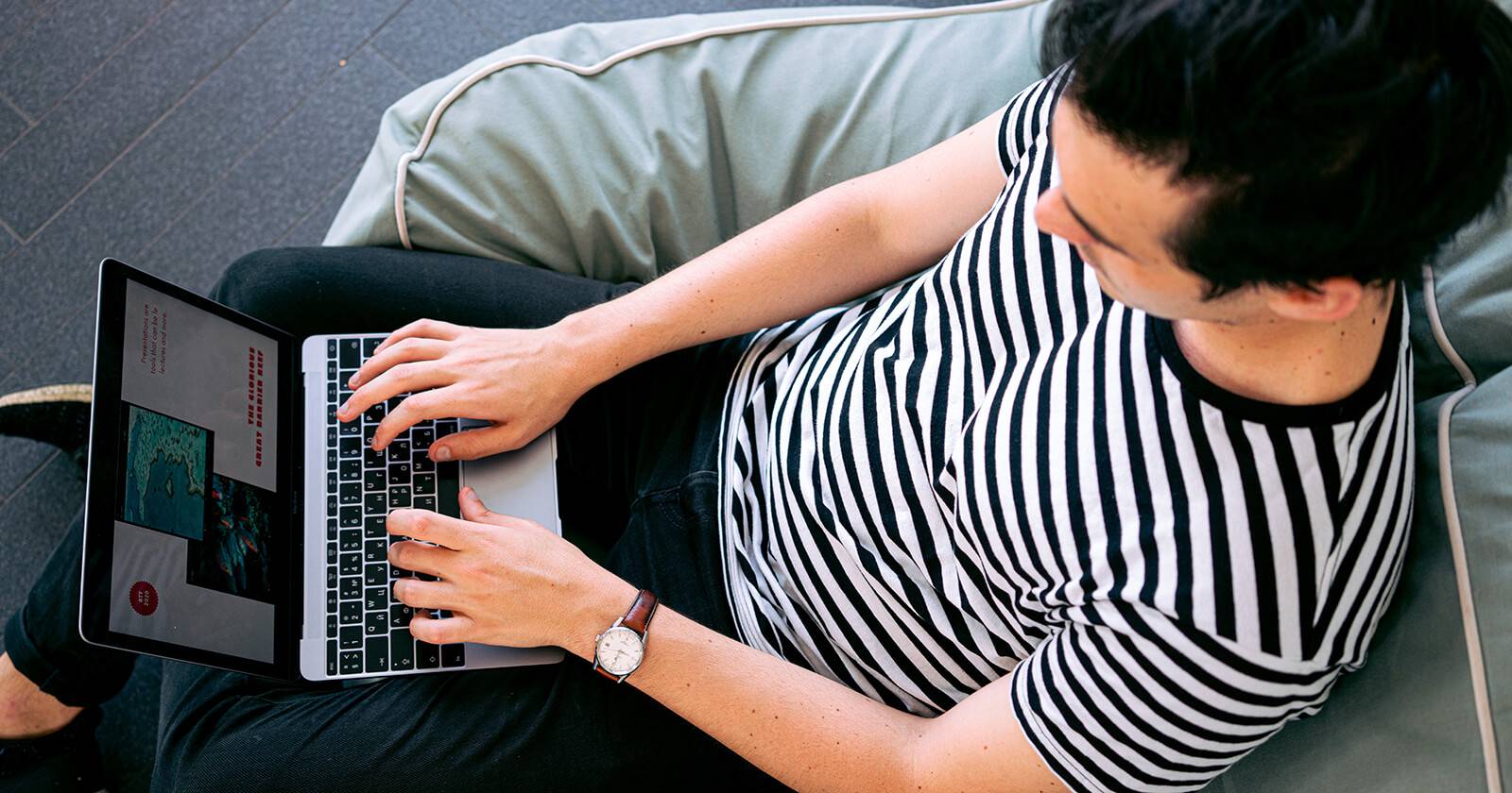 человек работает за ноутбуком на диване