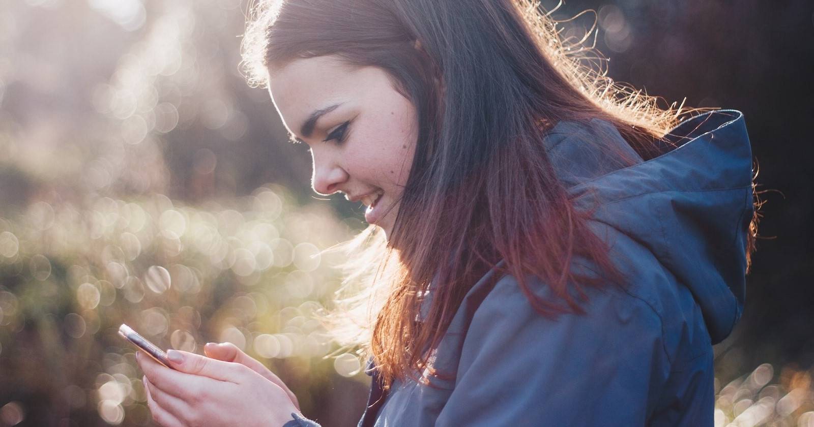 Женщина улыбается, глядя в смартфон