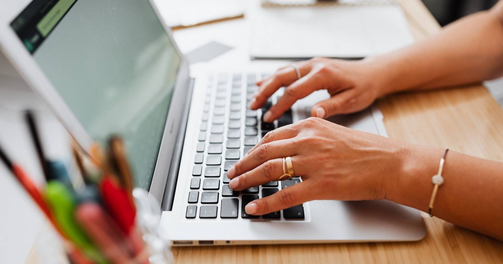 Человек печатает на клавиатуре MacBook, ноутбук стоит на столе
