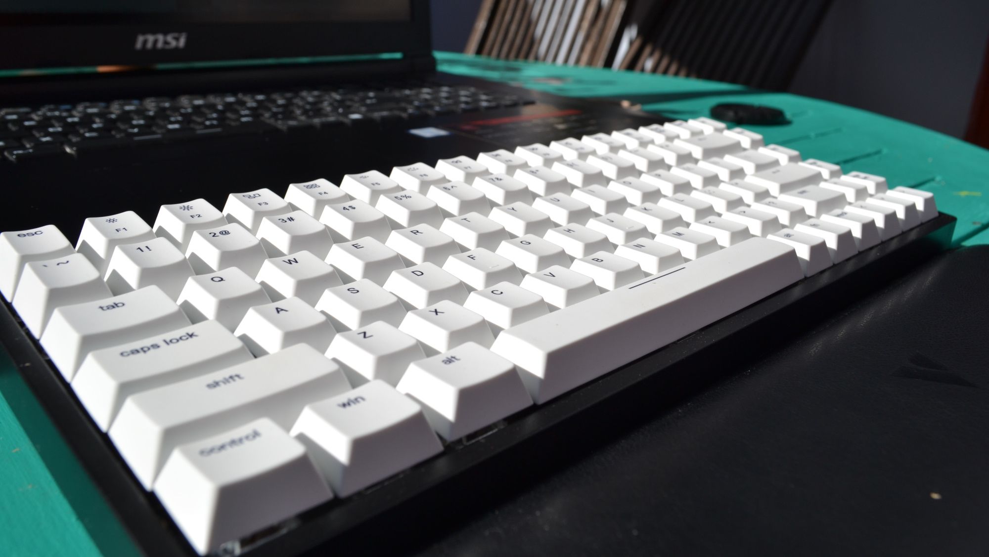 портативная механическая клавиатура Vissles V84 рядом с ноутбуком на улице