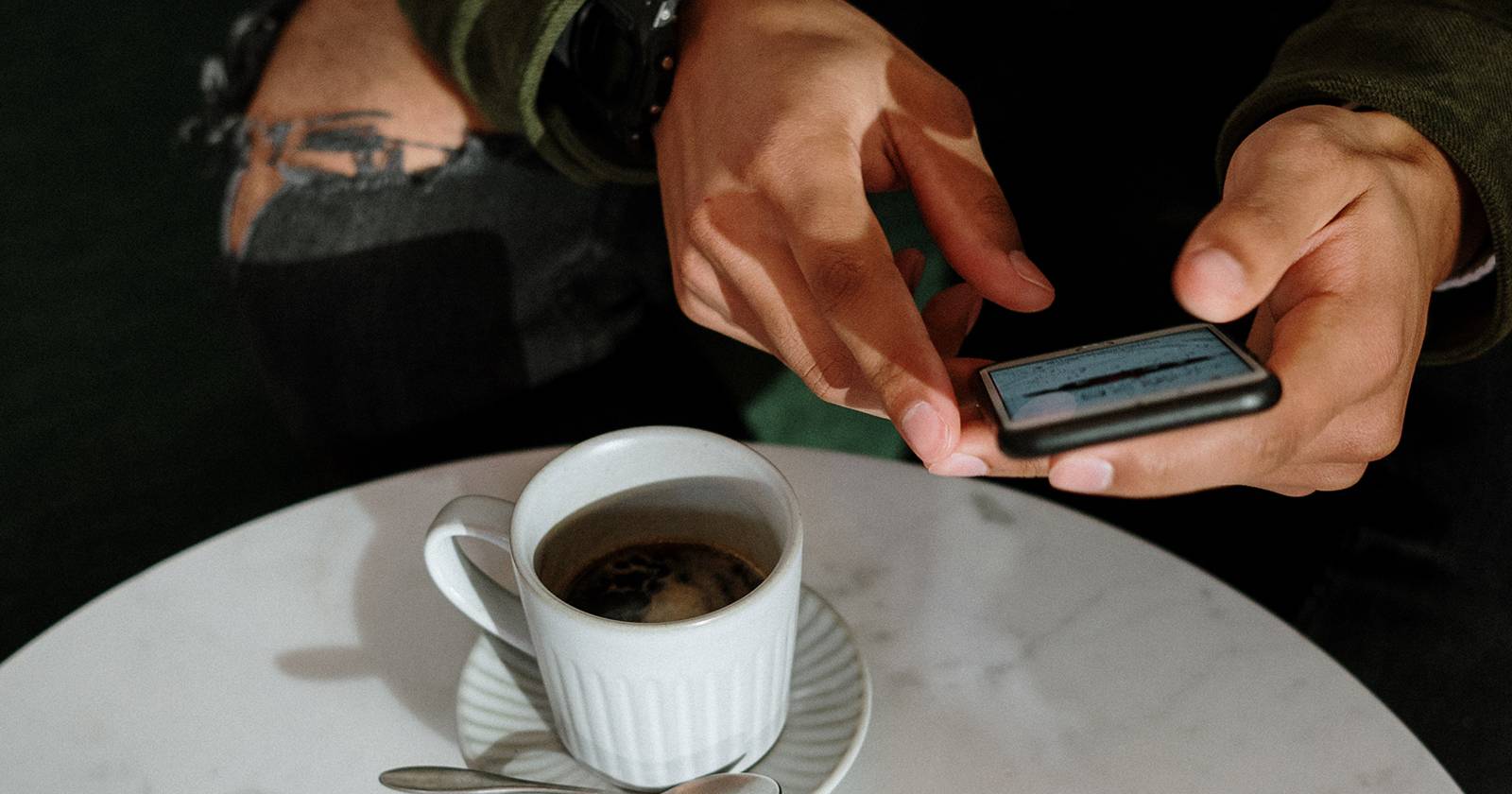 Мужчина использует iPhone с чашкой кофе
