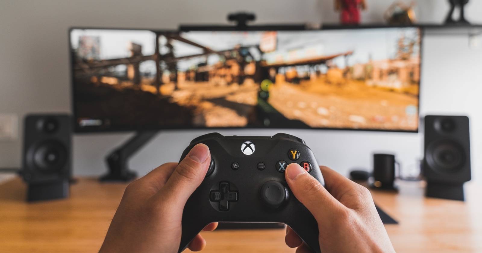 Человек держит беспроводной контроллер Xbox перед монитором