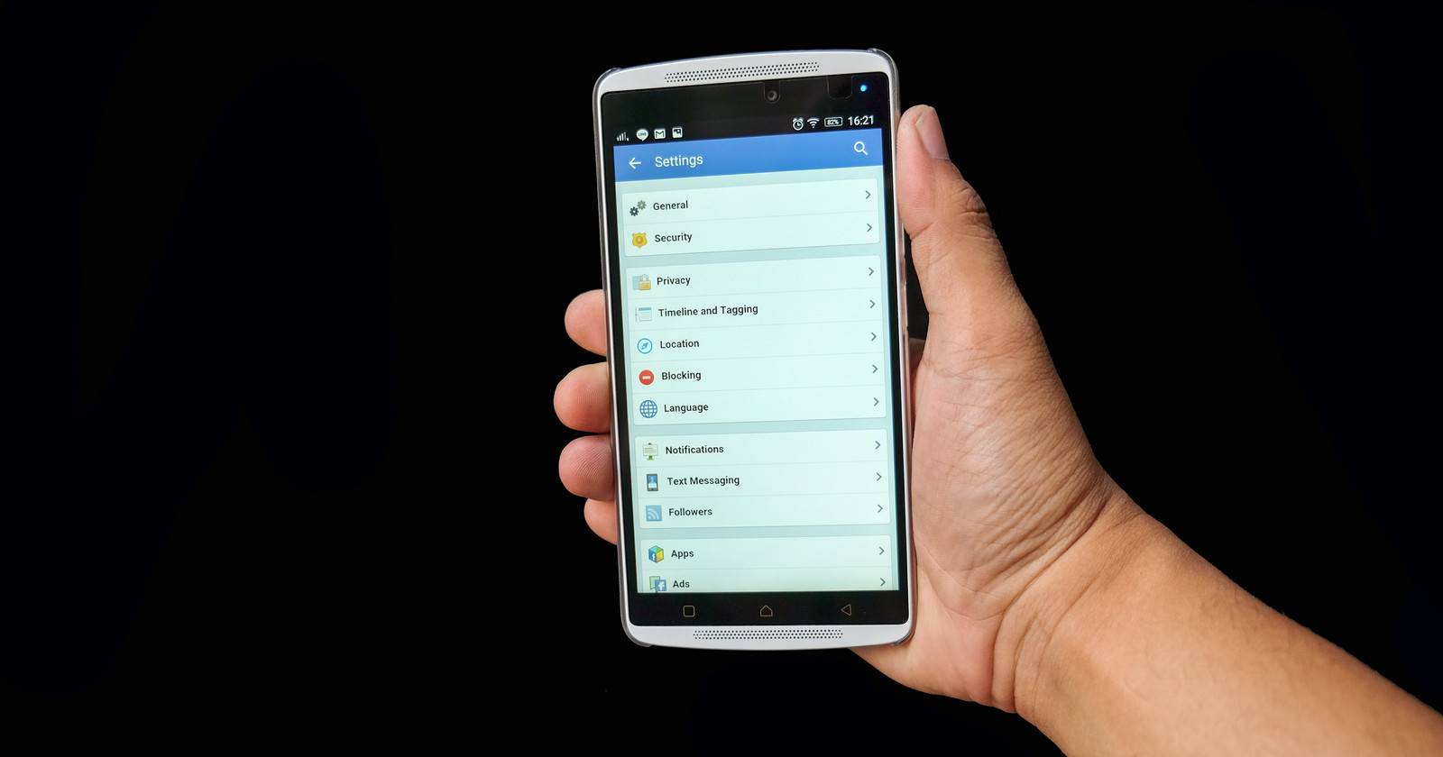 Рука держит Android-телефон с открытым меню настроек