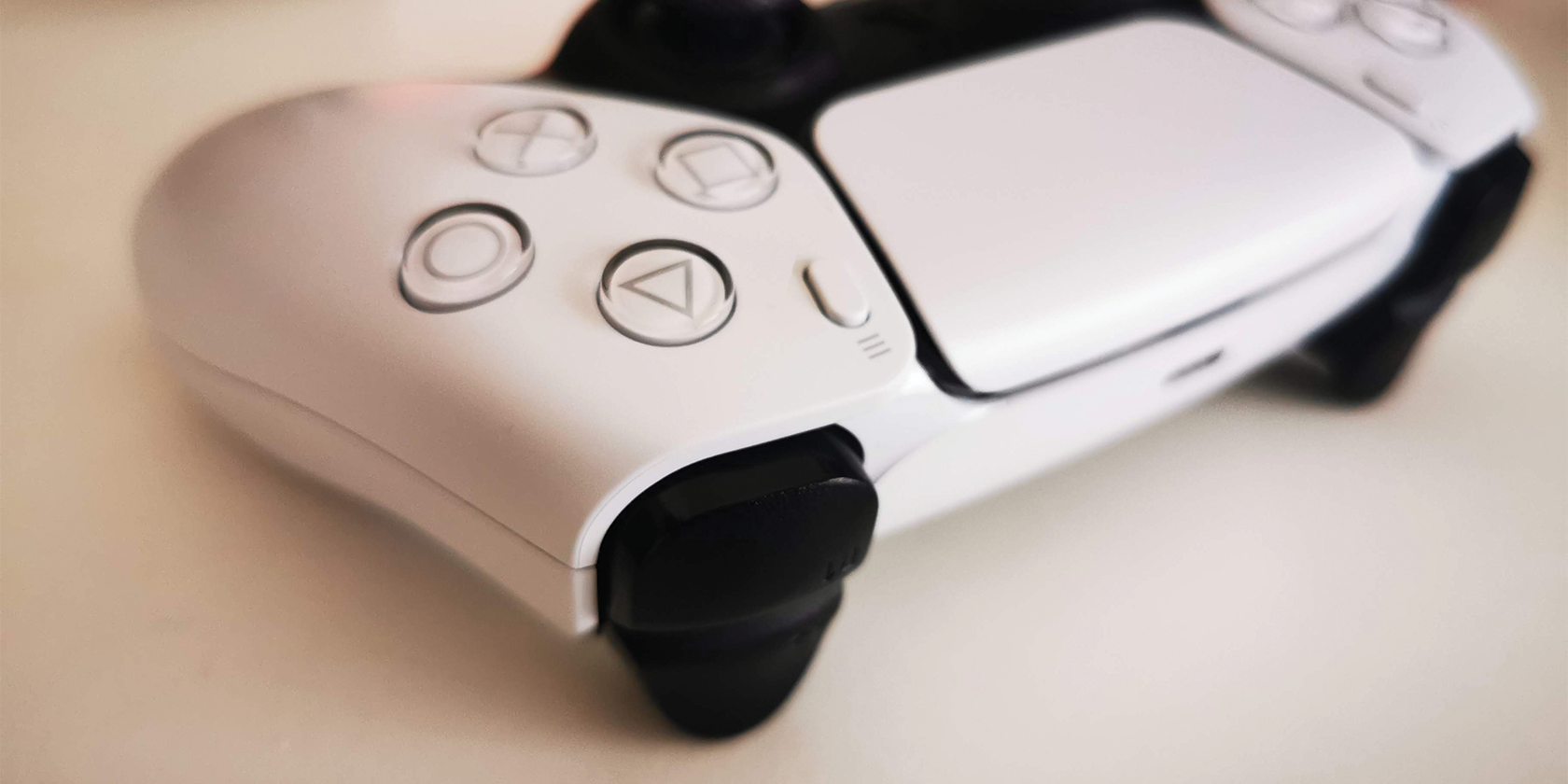 Джойстик PS5 на столе рядом с чашкой, пауза в игре