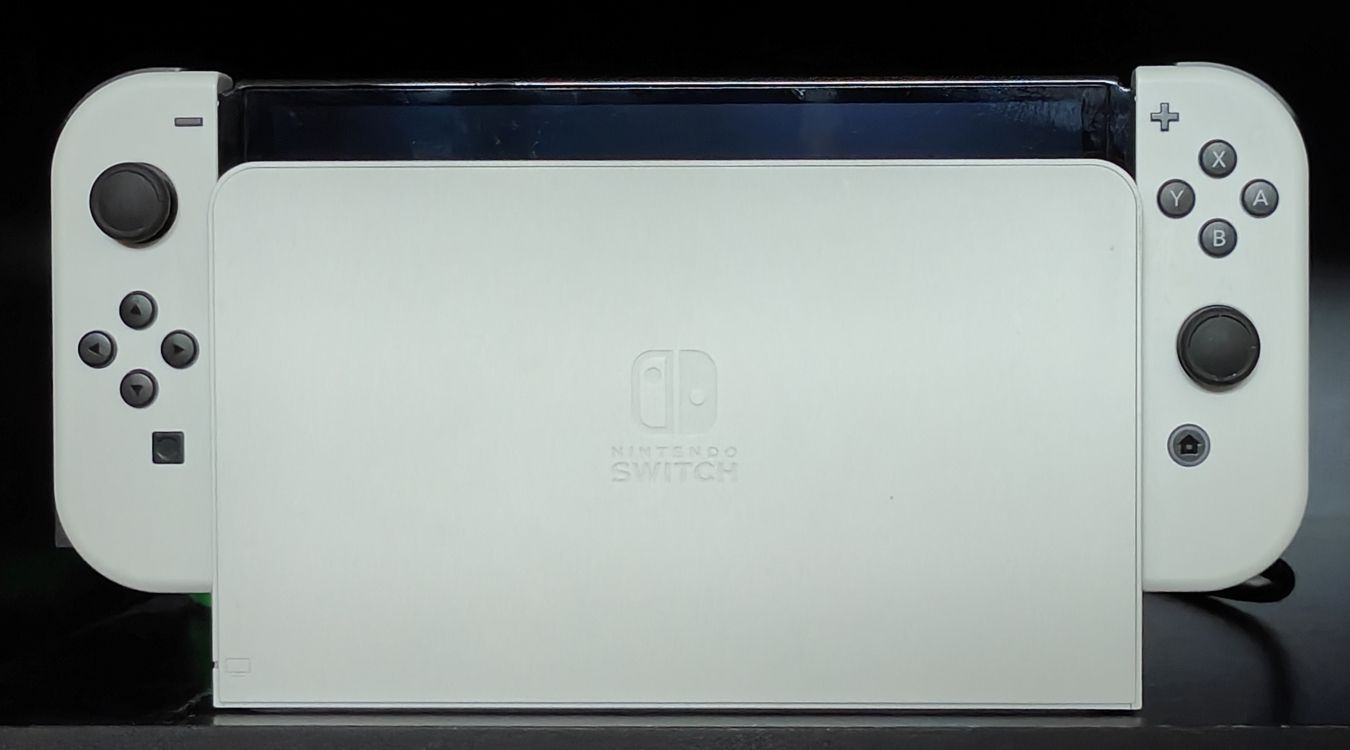 A photograph of a docked Nintendo Switch OLED console