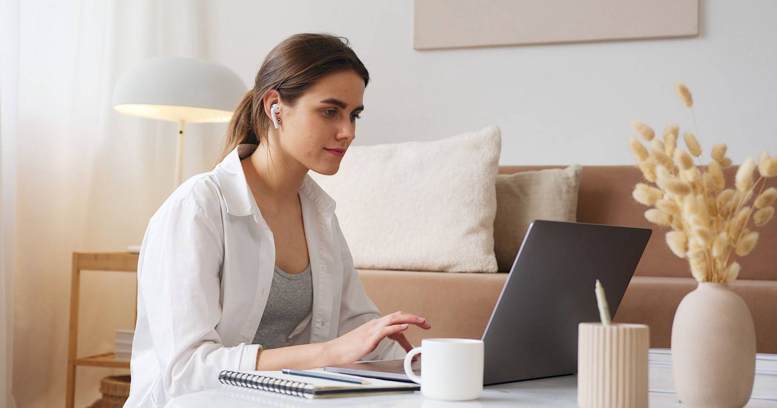 Женщина в наушниках работает за ноутбуком