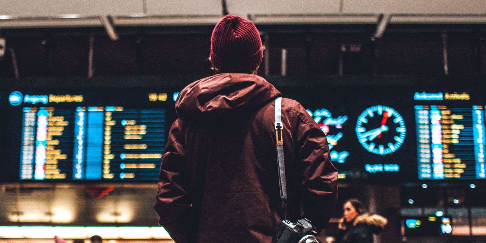 Человек стоит перед табло с прибытиями