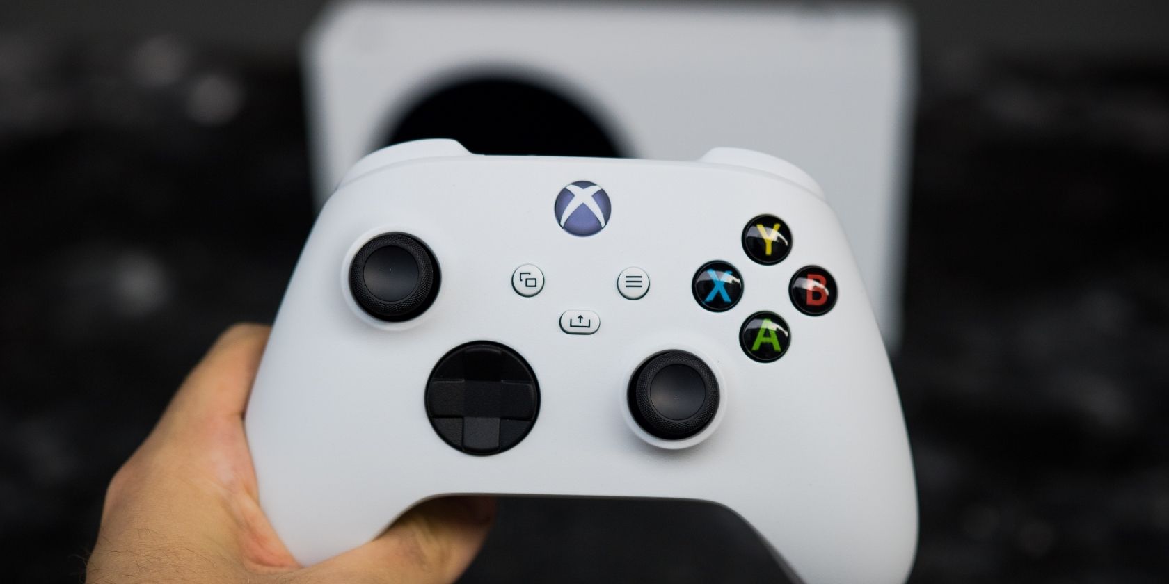 Геймпад Xbox Series S на переднем плане, размытый корпус консоли позади