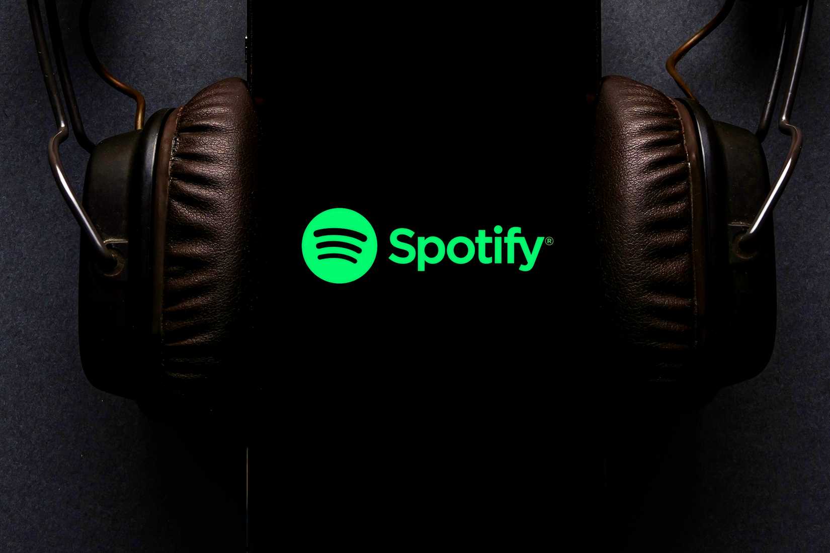 Spotify на экране смартфона с наушниками, подключёнными к телефону