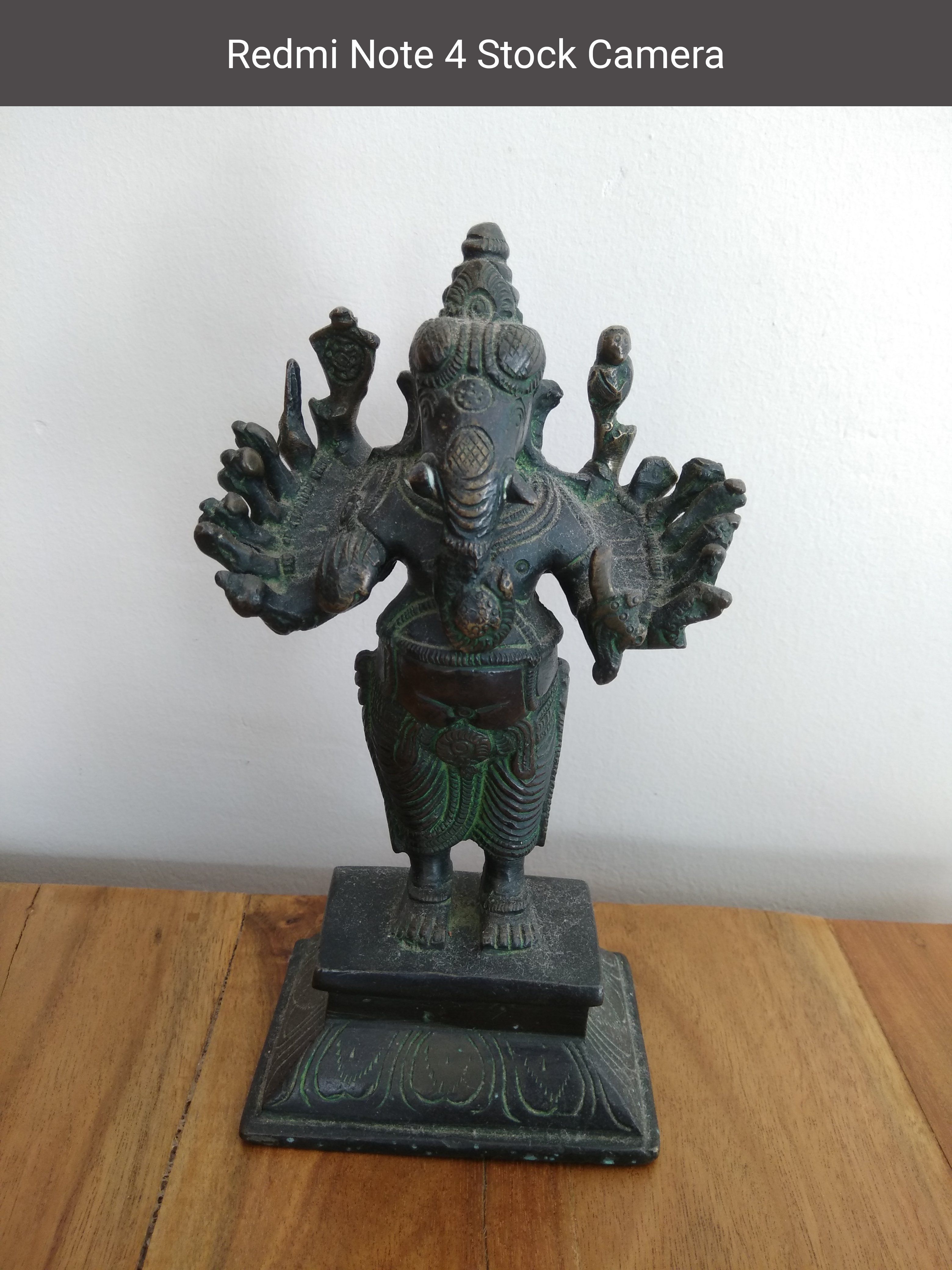 Металлическая статуэтка бога Ганеши на деревянной поверхности