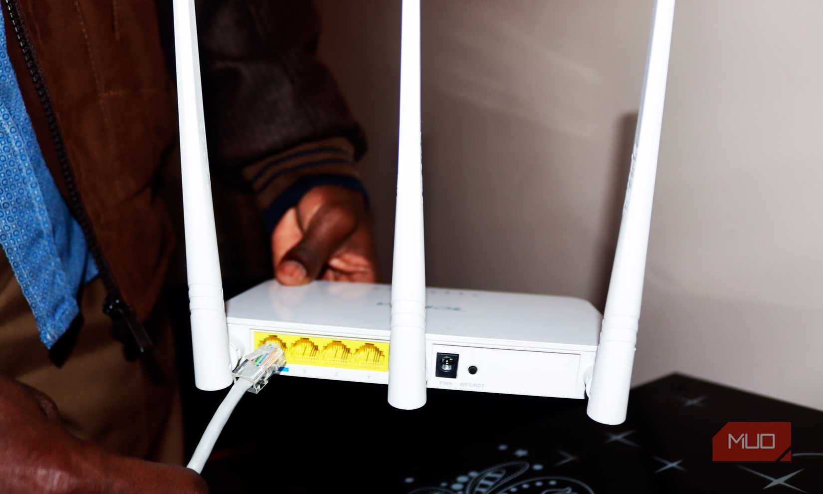 A man holding a Wi-Fi router and trying to connect an Ethernet cable