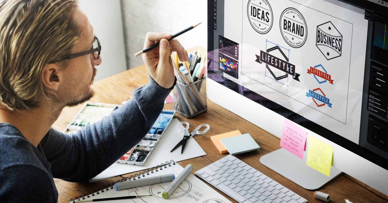 Мужчина разрабатывает логотипы на компьютере Mac