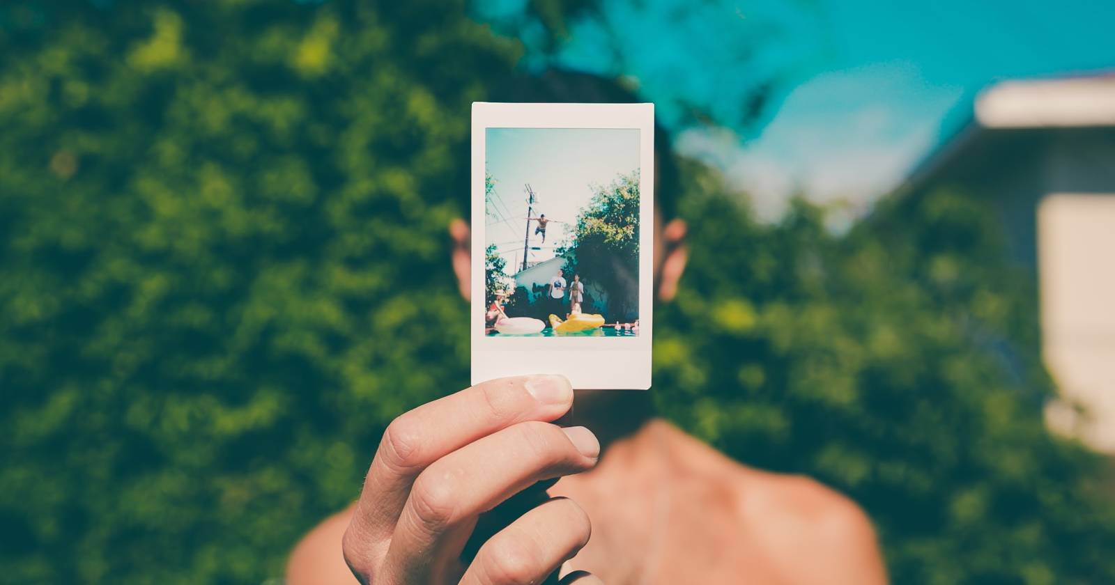 Человек, держащий полароидную фотографию перед лицом