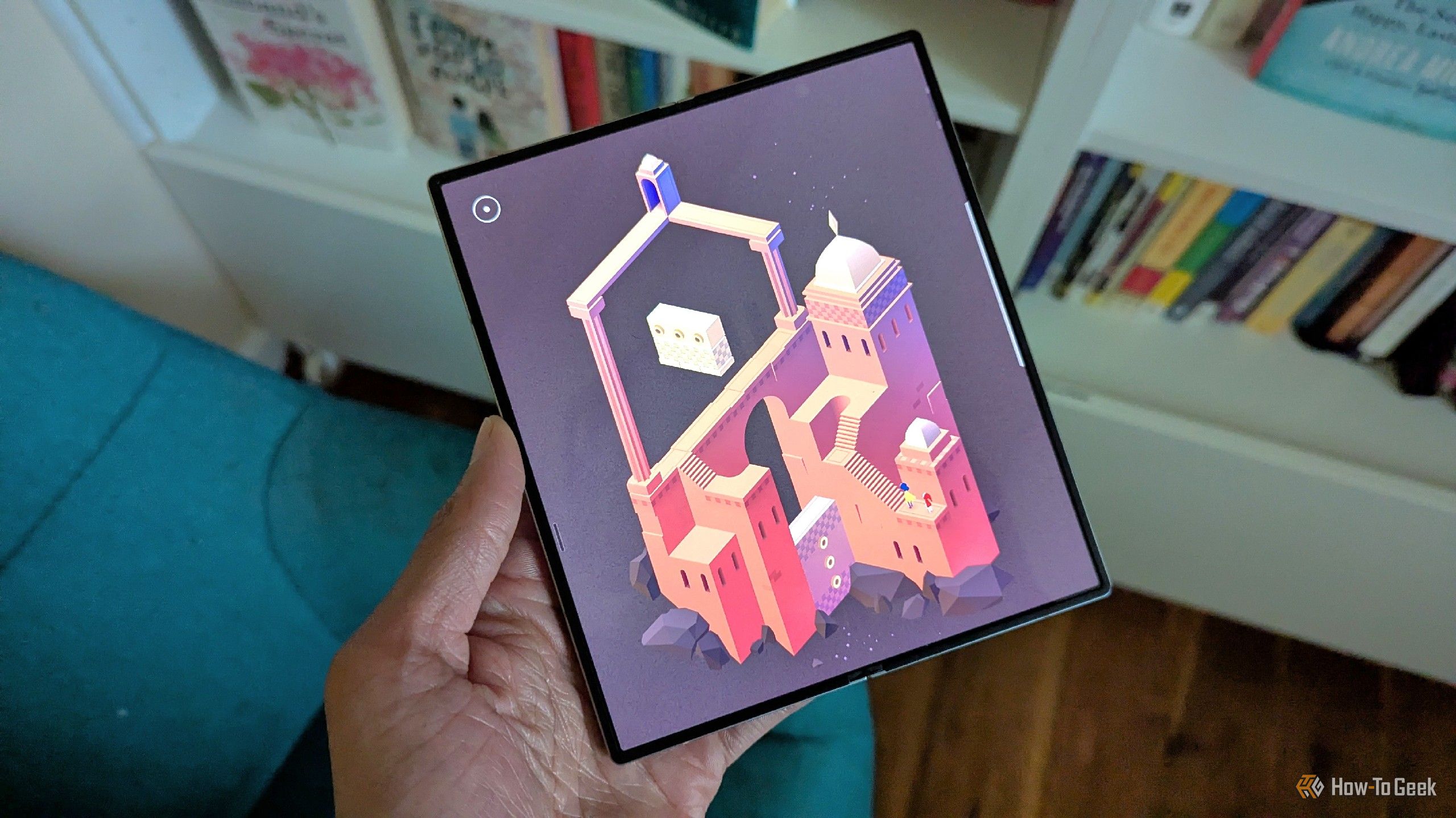 Monument Valley 2 on a Galaxy Z Fold 6 with books in the background.