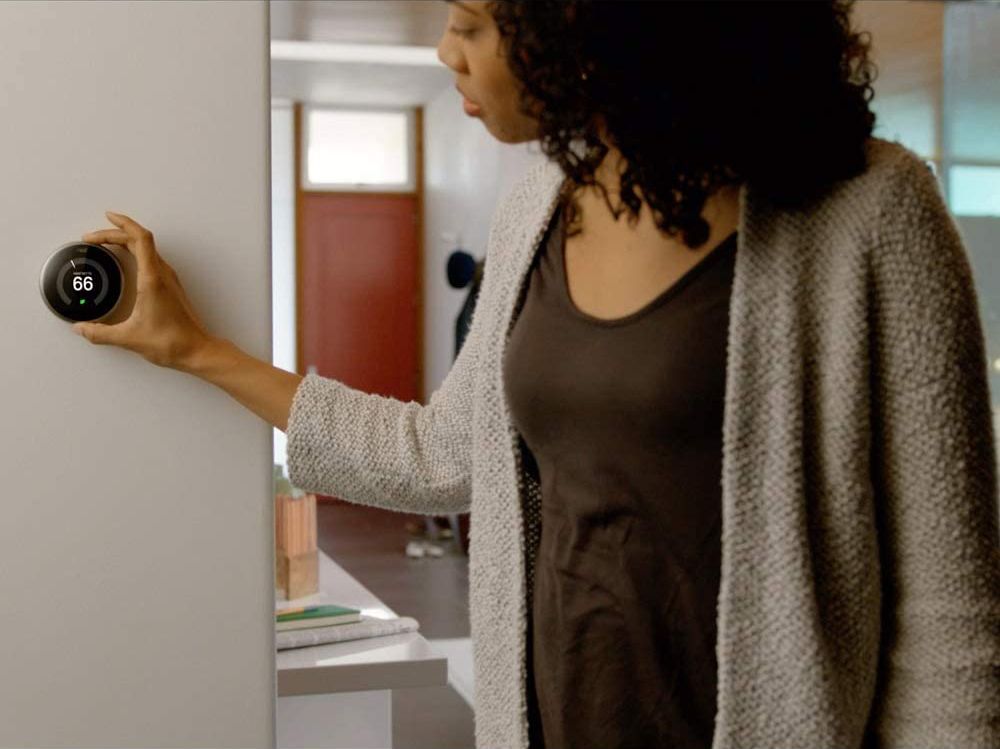 Woman adjusting Nest Thermostat