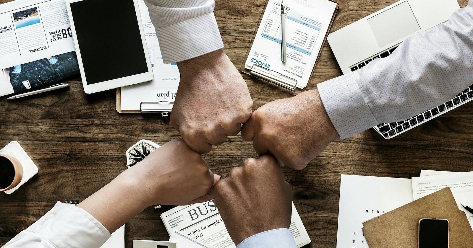 четверо людей стучат кулаками в офисе