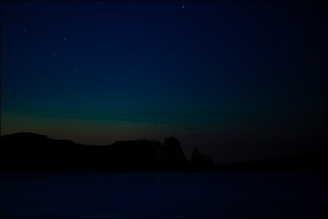 Ночное фото с едва заметной атмосферной свечением у моря