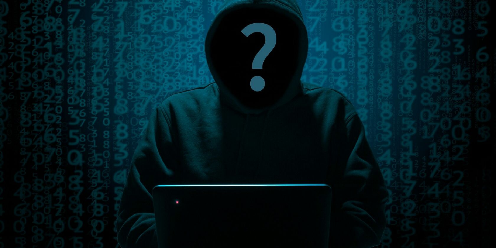 Анонимный хакер в капюшоне за ноутбуком.