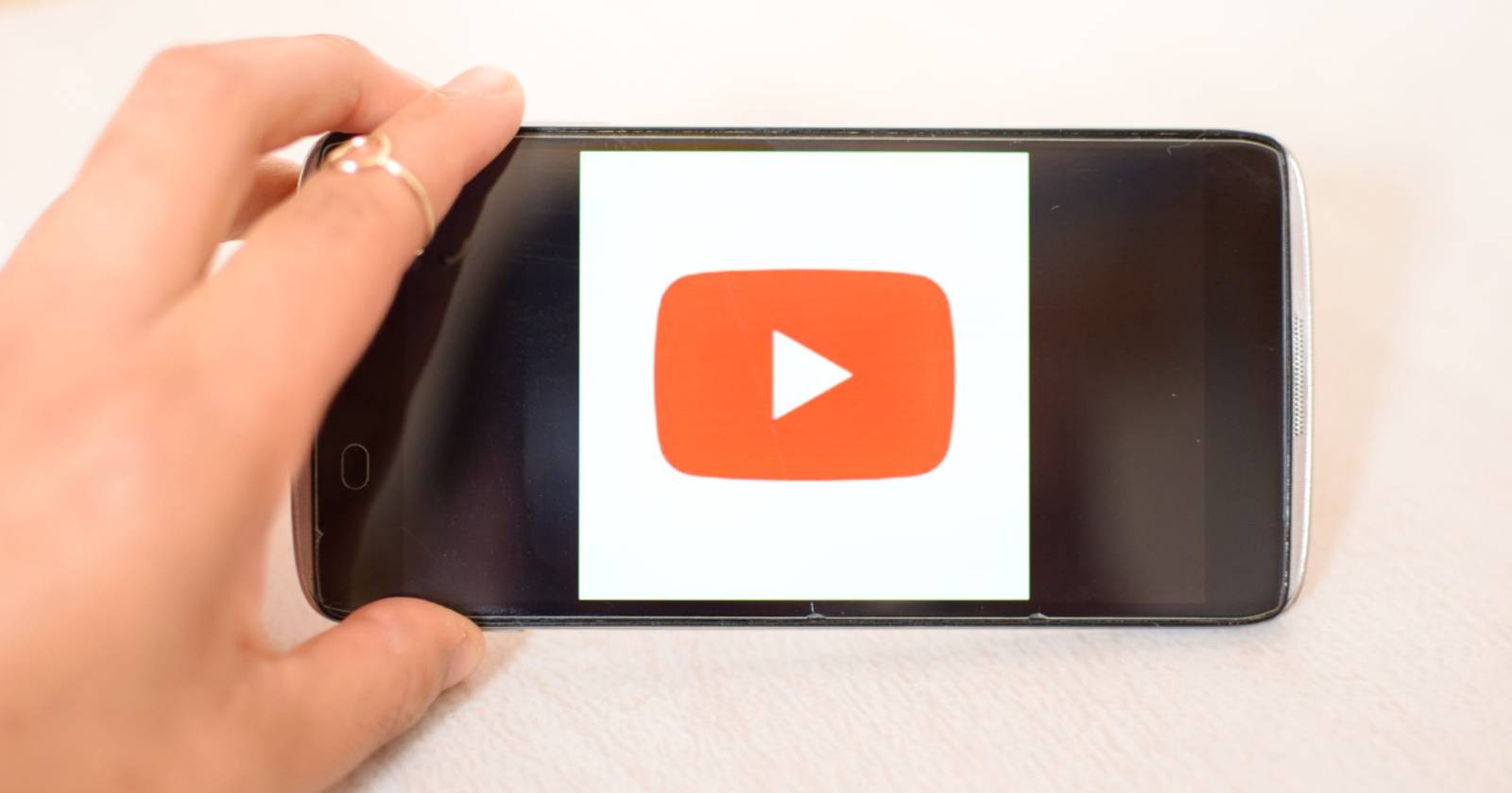 Рука держит телефон с логотипом YouTube