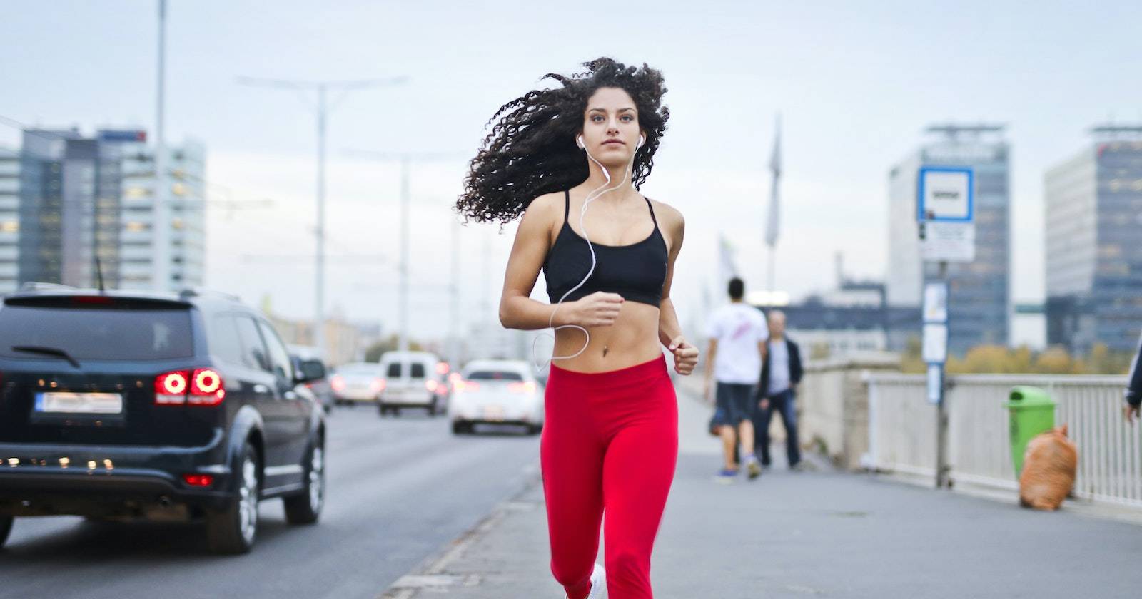 Женщина в наушниках слушает музыку во время пробежки по тротуару