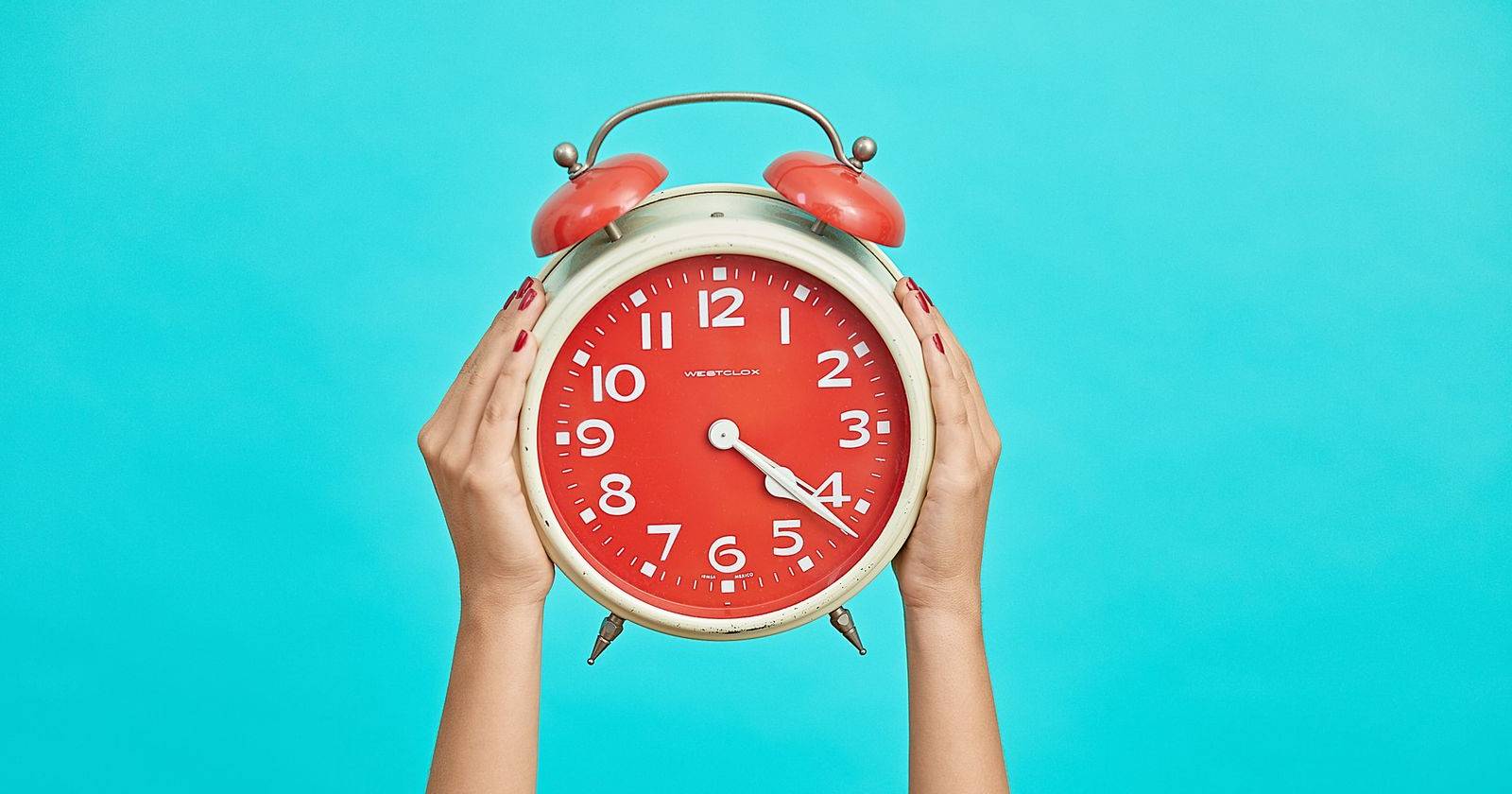 человек держит будильник перед экраном