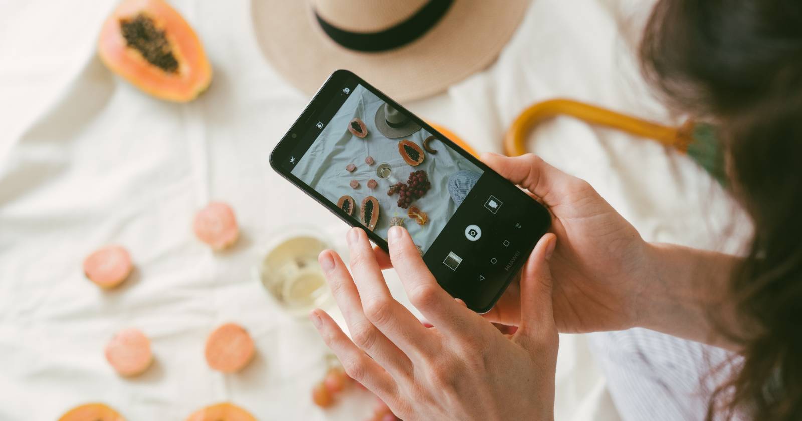 Женщина фотографирует фрукты на смартфон