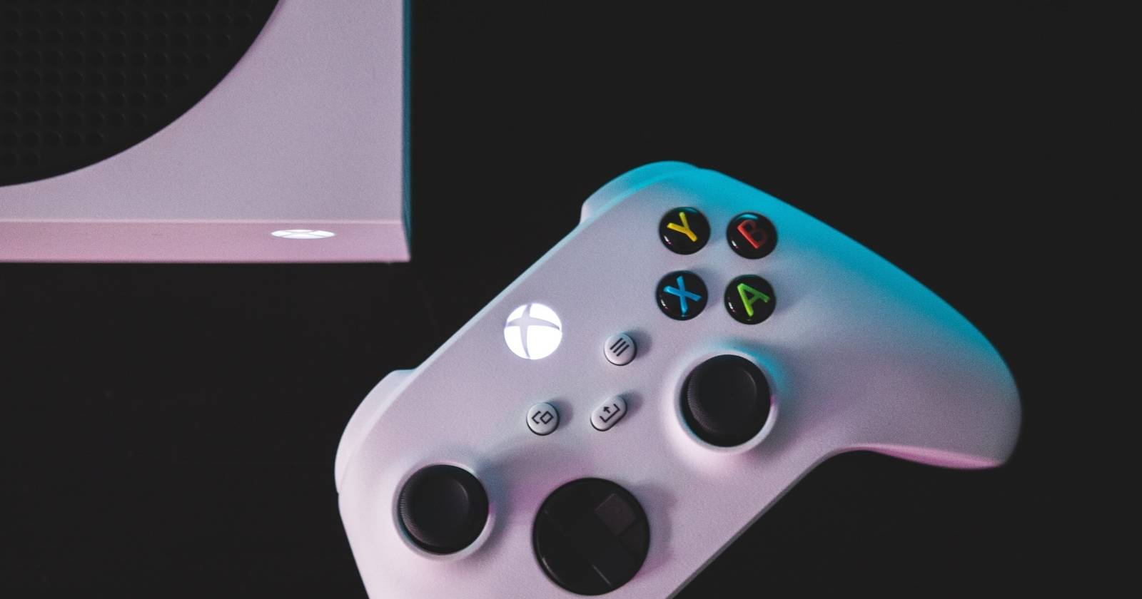 Фотография консоли Xbox Series S и контроллера на чёрной поверхности