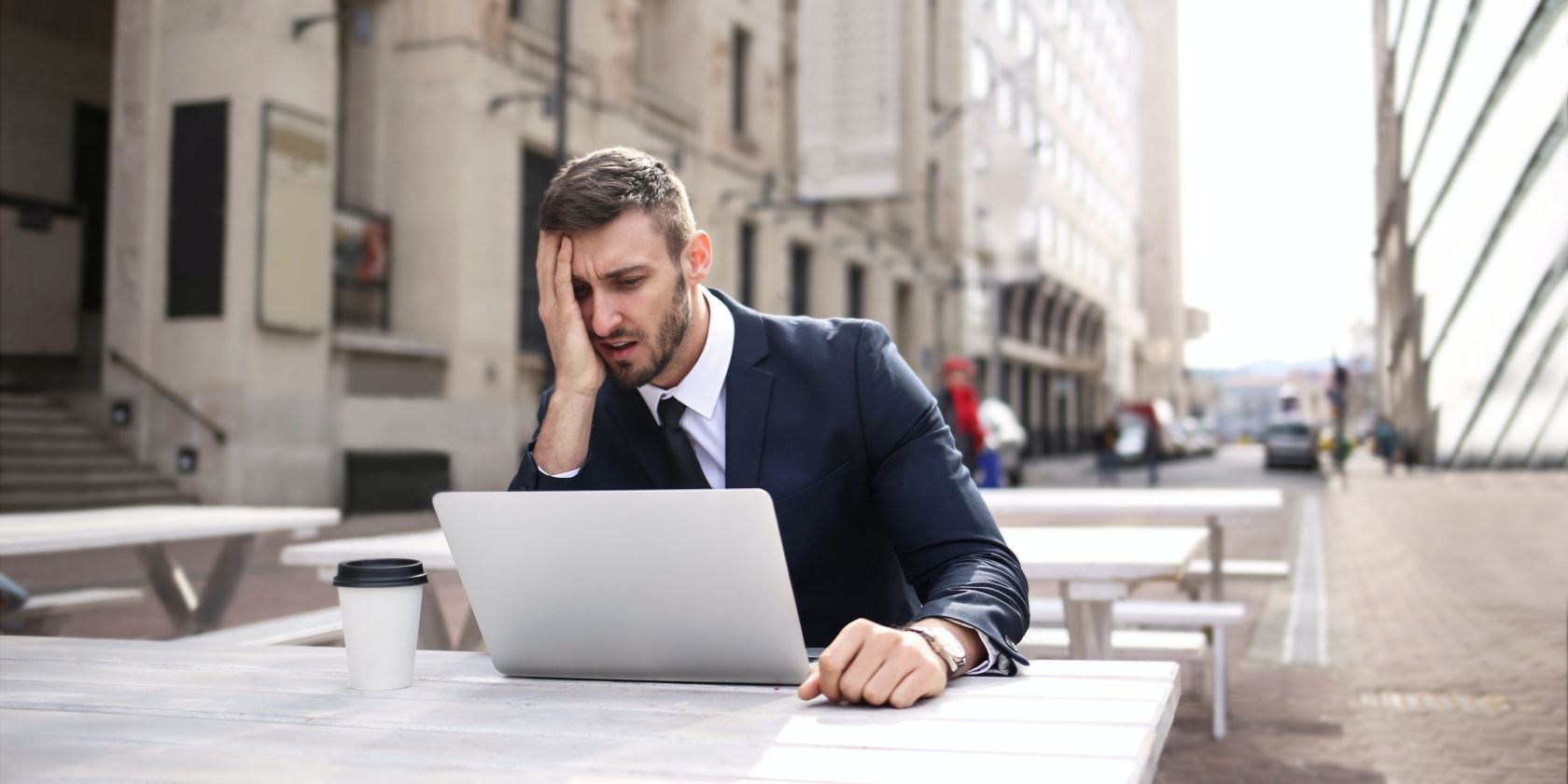 человек в черном костюме прикрывает лицо правой рукой