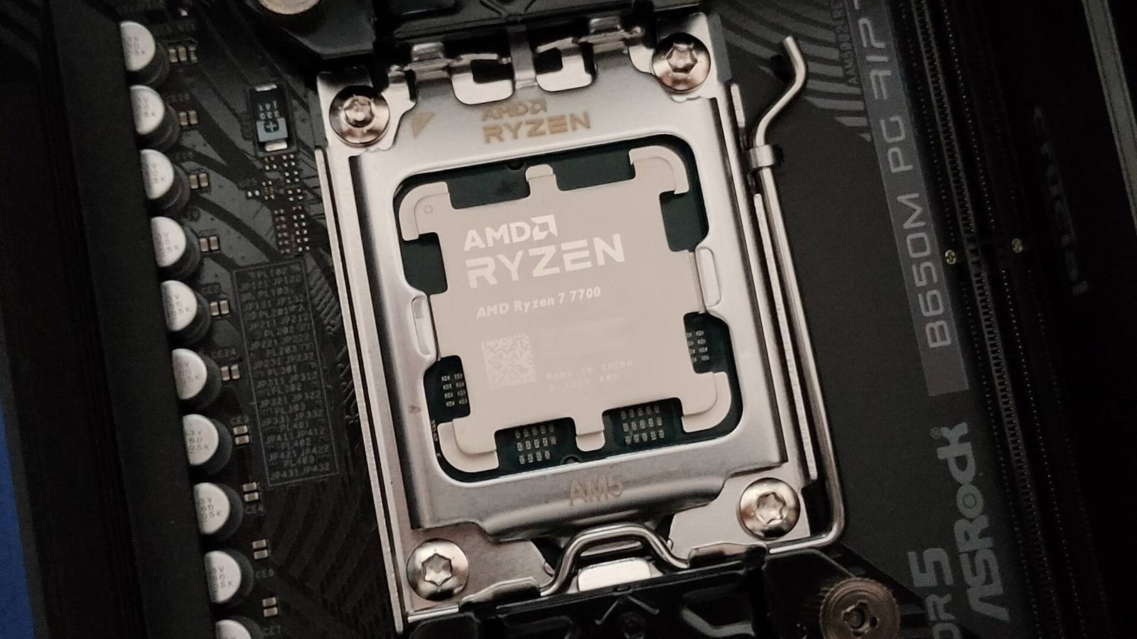 Крупный план процессора AMD Ryzen 7 7700 в разъёме AM5 и материнской платы ASRock B650M PG Riptide.