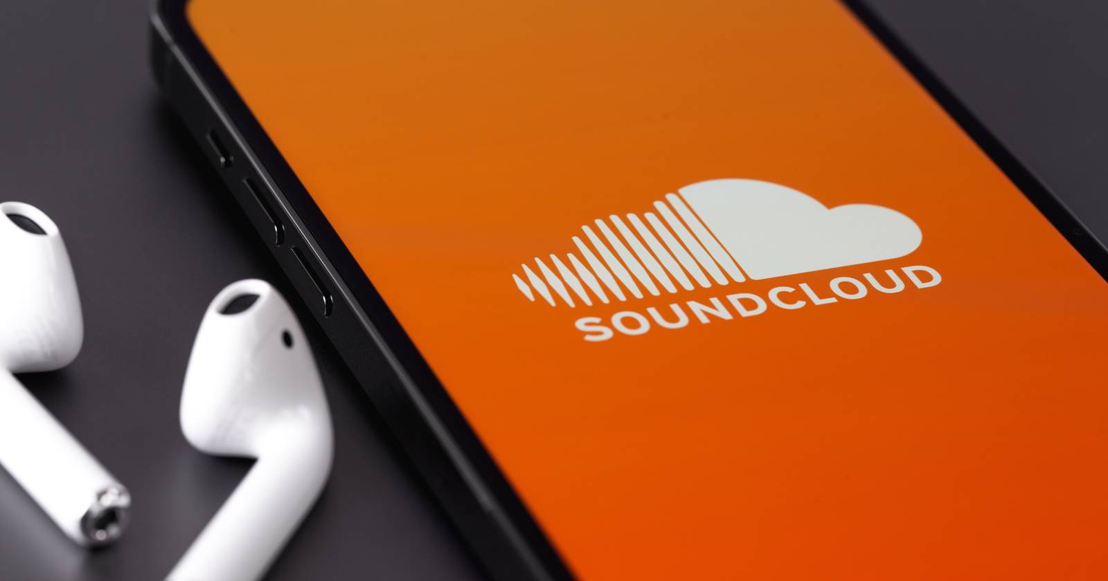 Логотип SoundCloud на экране телефона рядом с наушниками