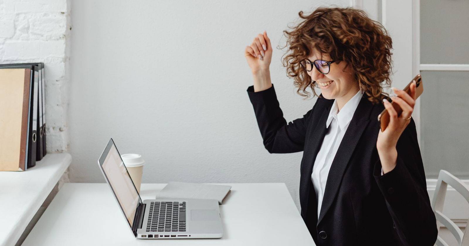 Женщина радуется перед ноутбуком на рабочем столе