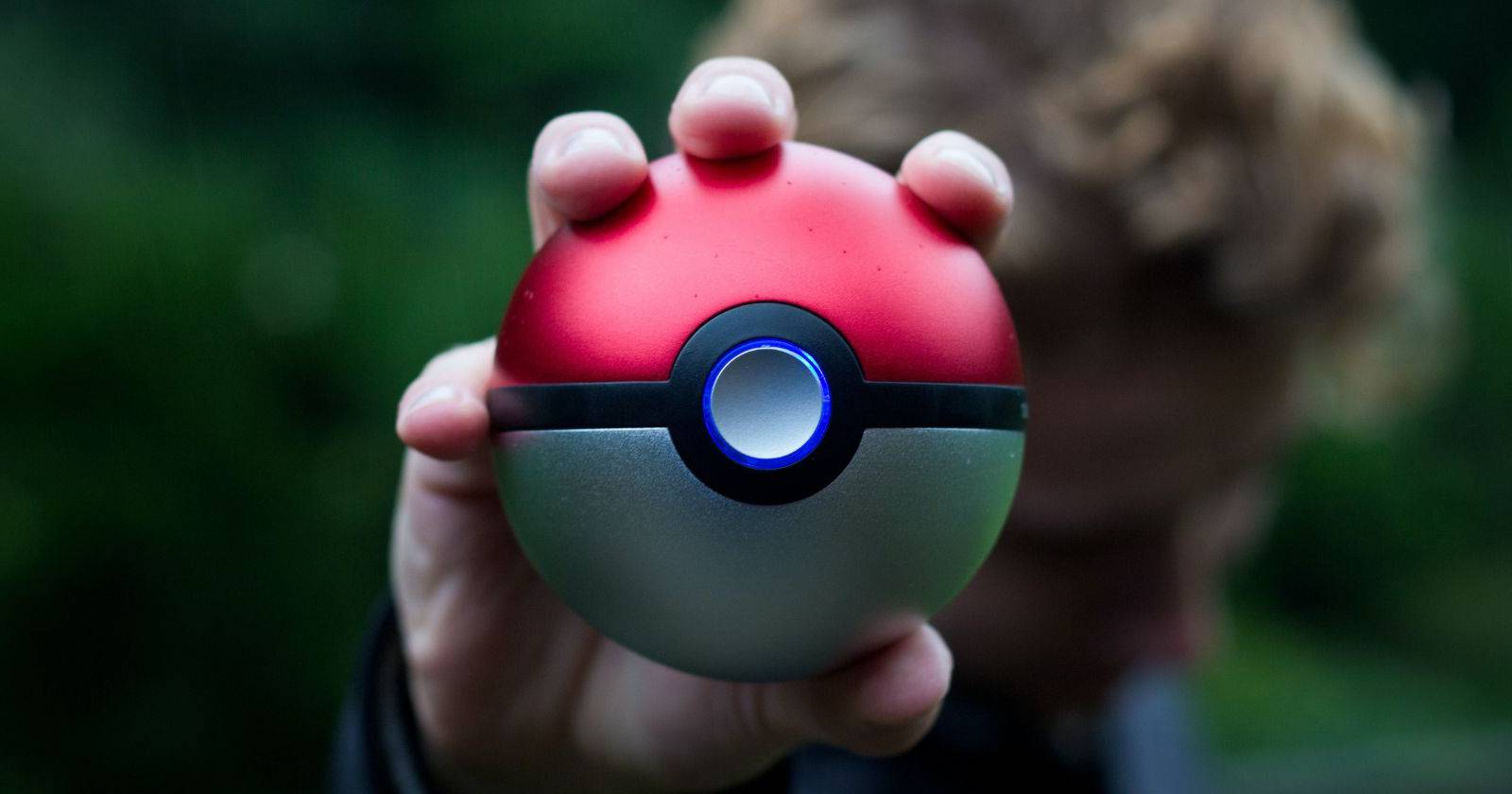 Человек на улице держит Poké Ball в руке