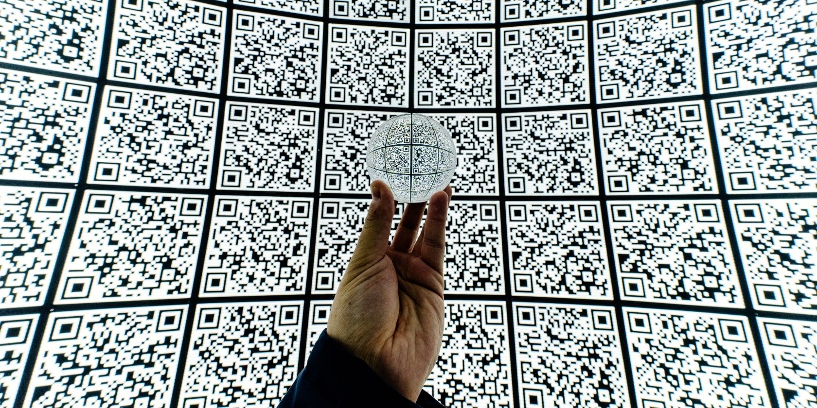 Человек держит распечатанный QR-код на фоне узора QR-кодов