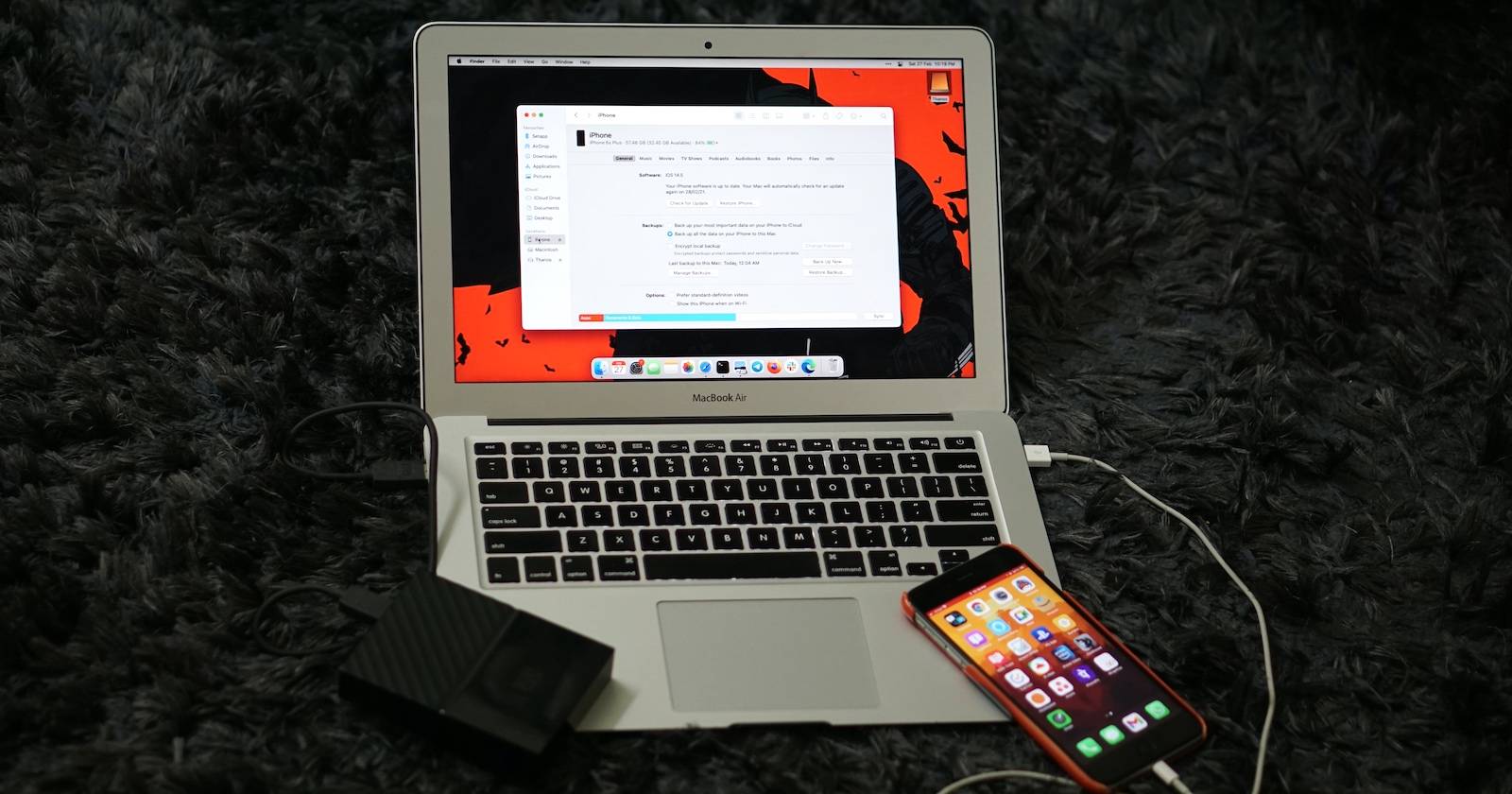 iPhone resting on a MacBook while completing a backup.