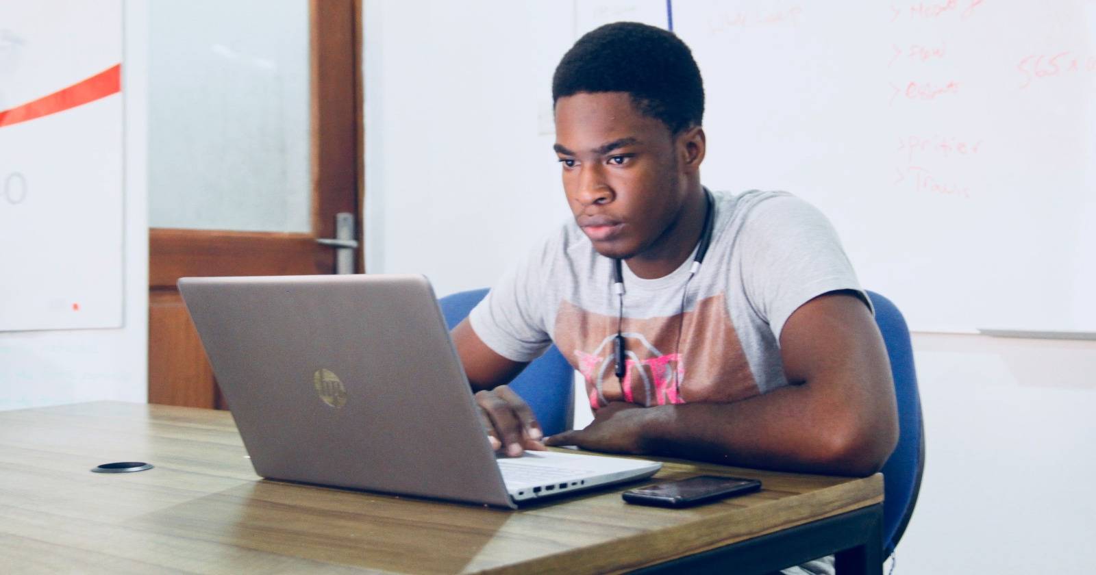 Студент за столом с ноутбуком, просматривающий материал.