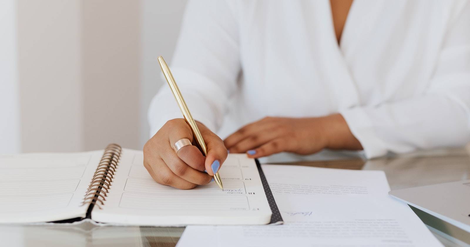 Человек в белой рубашке пишет в блокноте