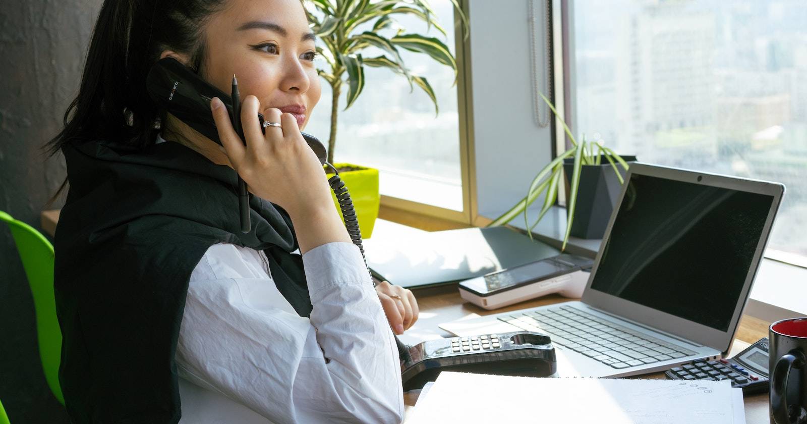 Женщина у рабочего стола во время телефонного звонка