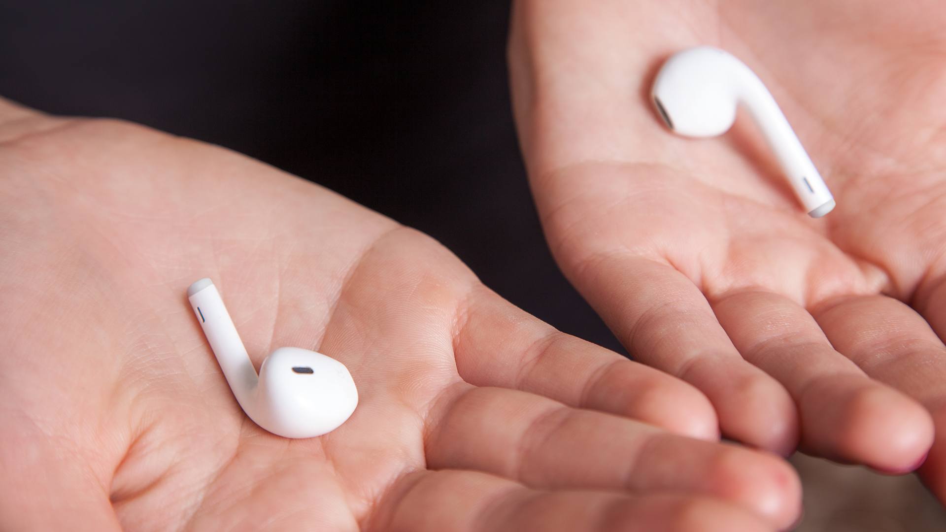 Руки держат наушники в ладонях