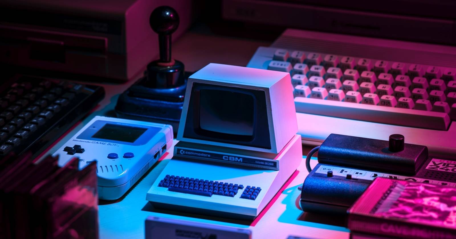 Фотография коллекции ретро‑консолей и игр при розово‑голубой подсветке